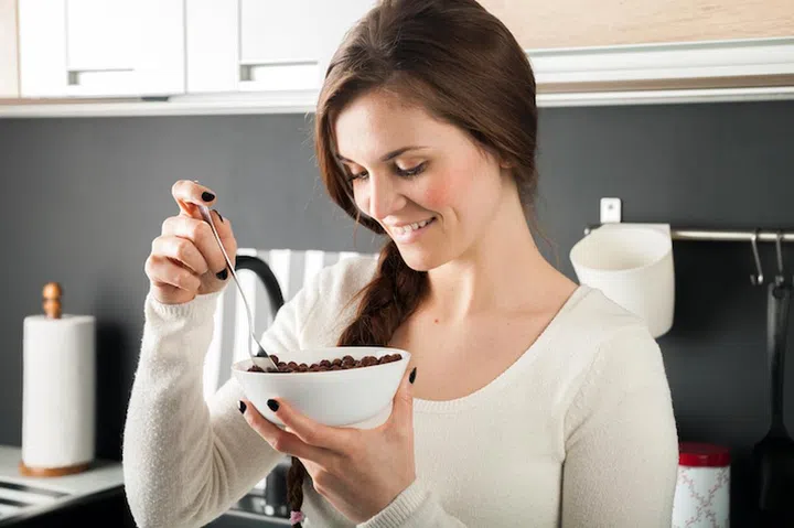 Woman with bowl of coco cereal in modern kitchen