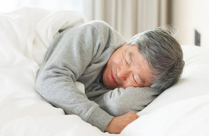 asian senior man lying on bed sleep well with smile in bedroom at home