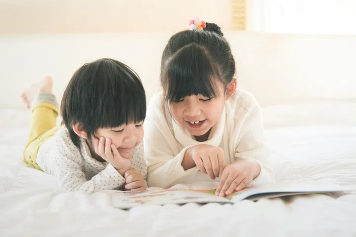 Cute asian children reading book on white bed,vintage filter