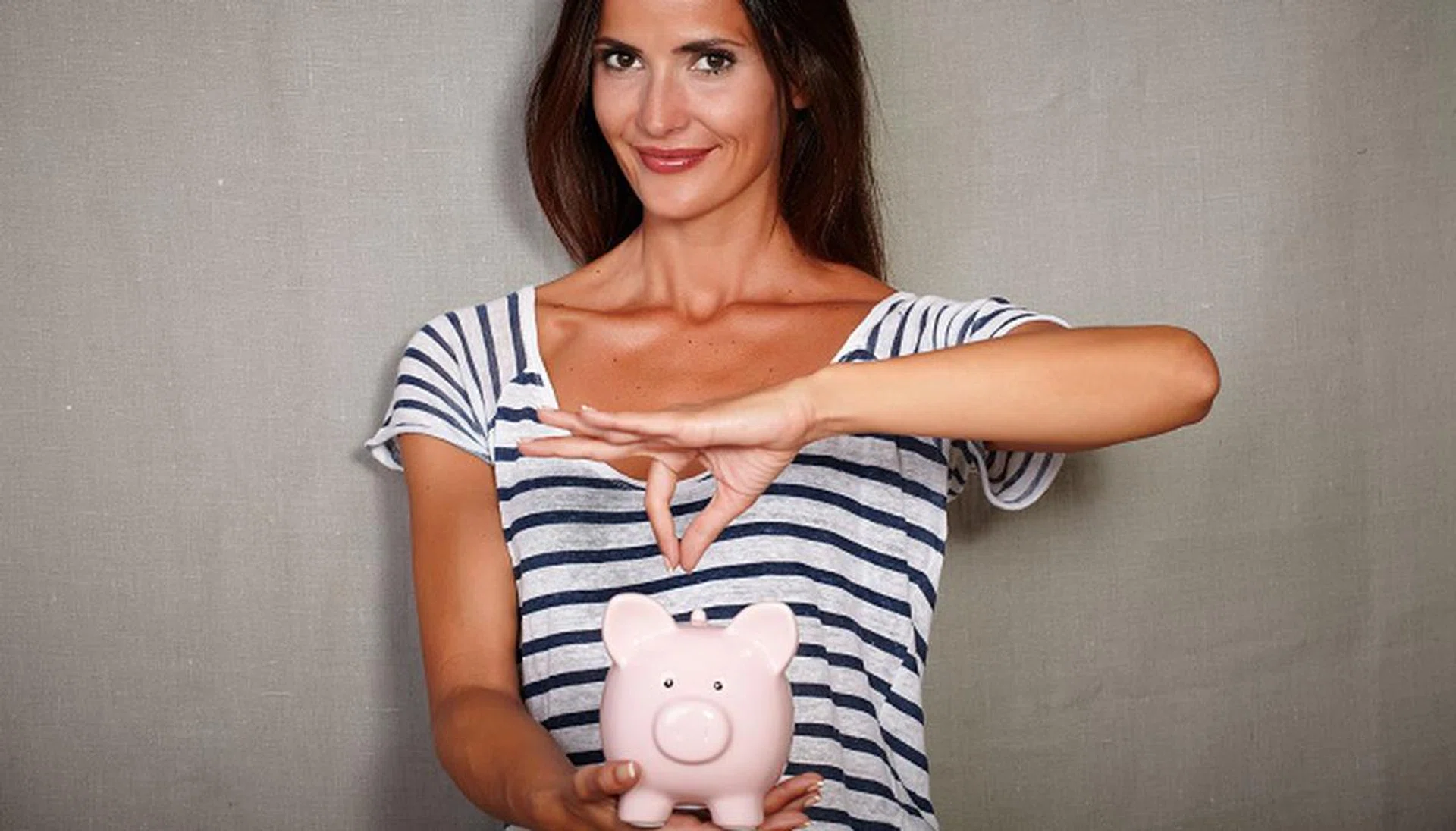 47505164 - waist up portrait of a happy woman in her 30s holding a piggy bank with savings