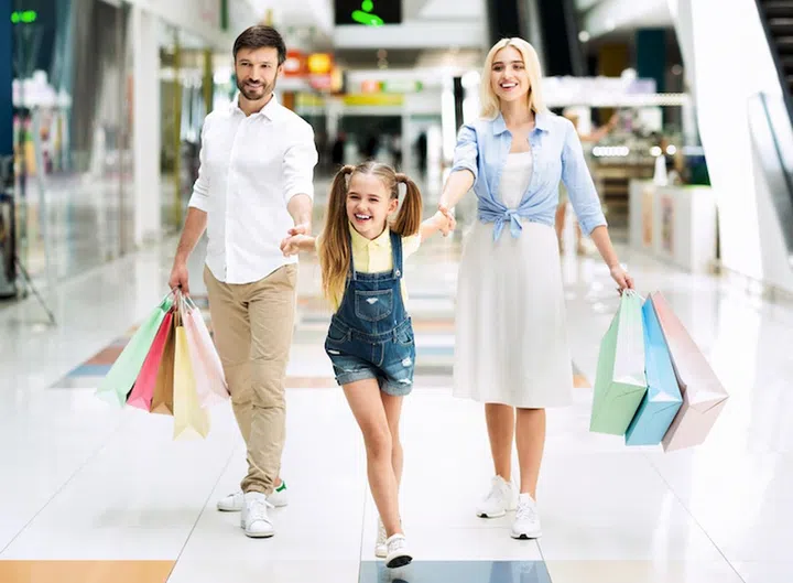 Sales Season. Family Of Three Carrying Shopper Bags After Successful Shopping In Mall.