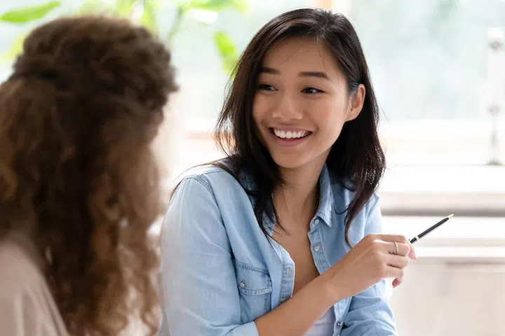 Asian student girl looking at group mate talking studying learn prepare for exam sitting in classroom, diverse friends employees working together on new project communicating discussing concept image