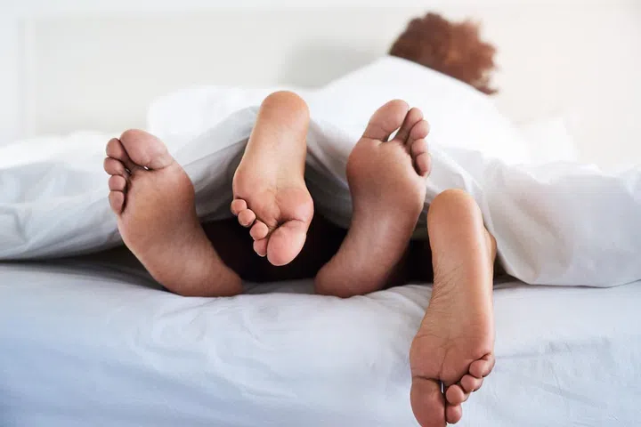 Shot of a couple’s feet poking out from under the sheets
