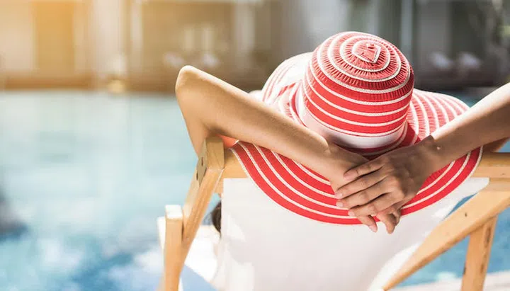 Woman is sitting in a chair relaxing in the summer, she is in the pool.