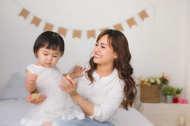 Happy loving family. Mom and child girl are having fun on the bed.
