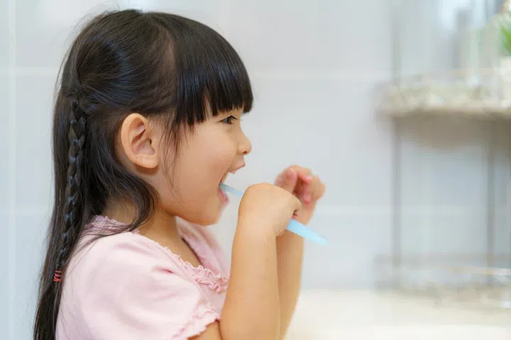 Asian cute child girl or kid brushing her teeth by toothbrush in the bathroom. Dental hygiene Healthcare concept.