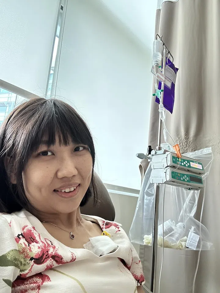 Alison at a chemotherapy session. The medication enters her body via a chemo port inserted at her upper chest. Photo credit: Alison Wee