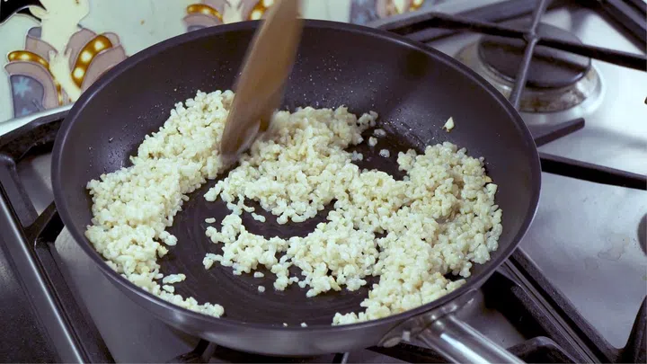 02. Over medium/high fire, heat a frying pan or wok with 1 tablespoon of oil. Oil should be hot, but not smoking. Add minced garlic. Keep stirring for about 3 minutes, so it goes light golden, but does not burn. Add in rice – keep stirring and tossing rice for about 2 minutes, so hot oil coats every grain.