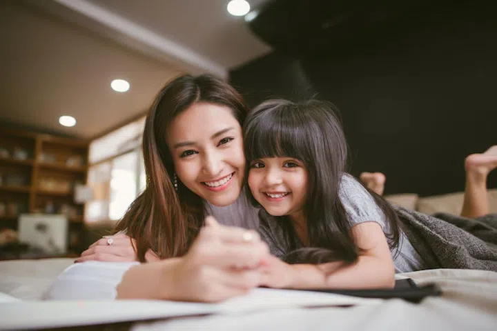 Portrait of mother and daughter playing and writing at home in the bedroom