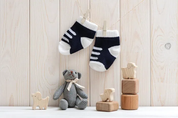 new baby socks hanging on clothesline over wood background, newborn and baby concept