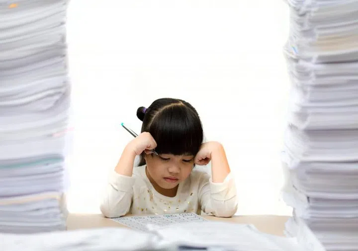 Little asian cute girl doing homework. big burden on students. overloaded child