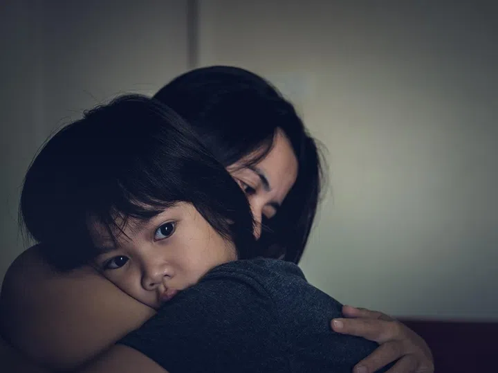 Mother and child, cute little boy resting on her mother's shoulder. Young mother holding her sad boy at home.