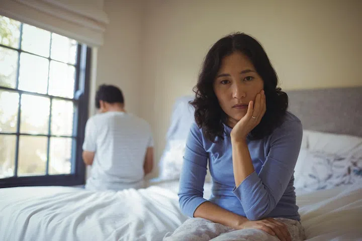 Couple ignoring each other in bedroom at home