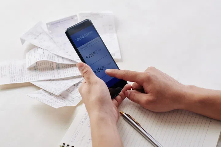 Close-up image of young man using banking application on smartphone when paying bills for apartment or house