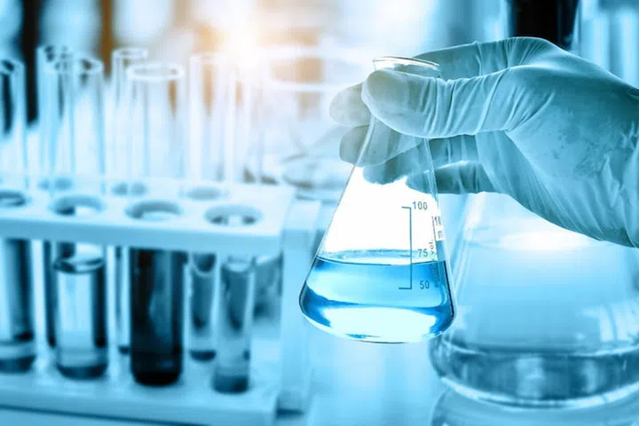 hand of scientist holding flask with lab glassware in chemical laboratory background, science laboratory research and development concept