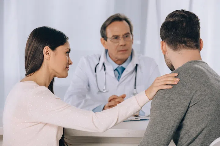 girlfriend hugging and supporting boyfriend at clinic