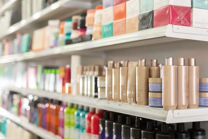 Bottles and boxes of different hair care products on store shelves in supermarket