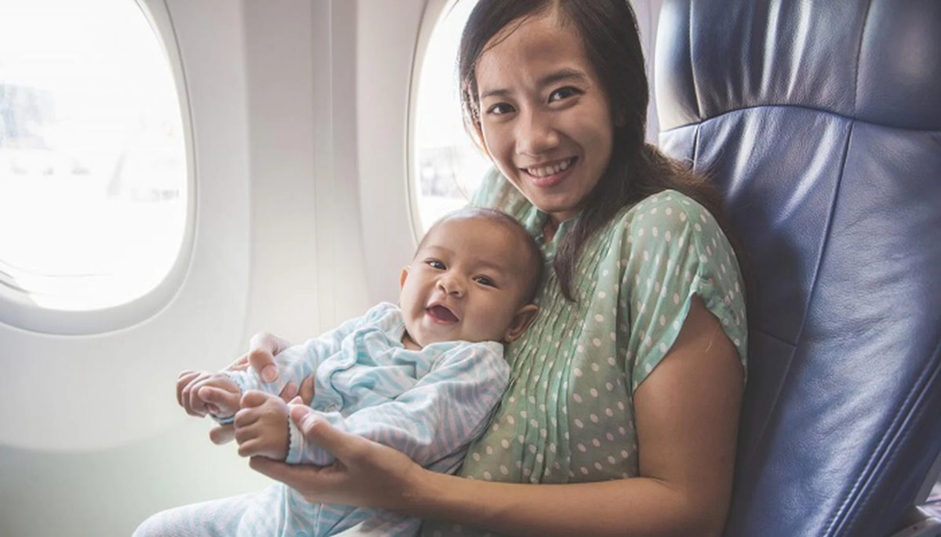 50512715 - happy mother and baby sitting together in airplane cabin near window