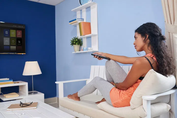 Young woman sitting on sofa and watching tv at home
