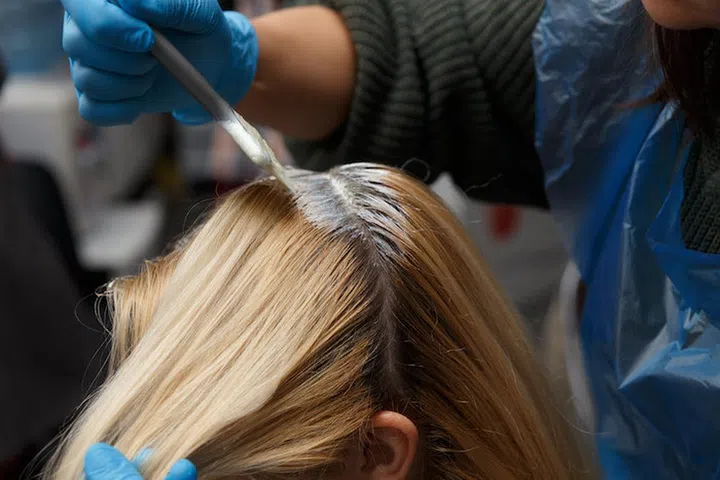 Hairdresser salon. Hair colouring in process. Woman dyeing hairs.
