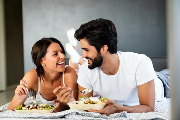 Healthy breakfast in bed. Young beautiful love couple is sitting in bed and having breakfast.
