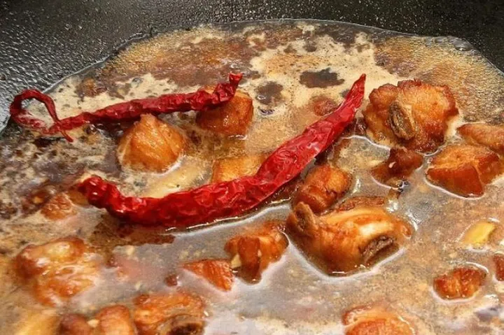 06. Place deep-fried ribs in the wok. Pour in the 900 ml of water and add the dried chillies.