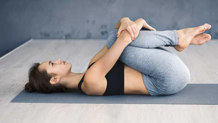 We're almost there – just two more yoga poses to go to help you improve your digestion. Now, continue to lie on your back. Bring your knees into your chest, and hug your knees with your arms.