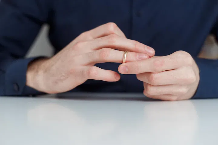 Young man is taking off the wedding ring. Close up view. Divorce concept.