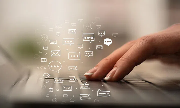 Business woman hand typing on keyboard with chat icons around