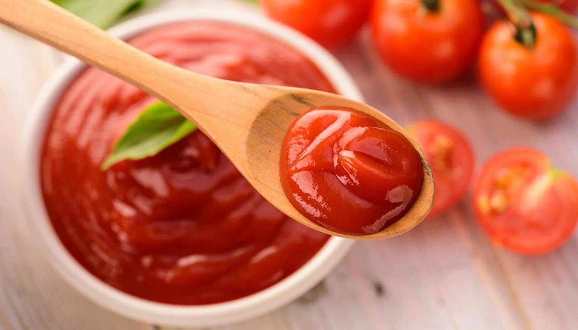 bowl of ketchup or tomato sauce and fresh tomatoes on wood table