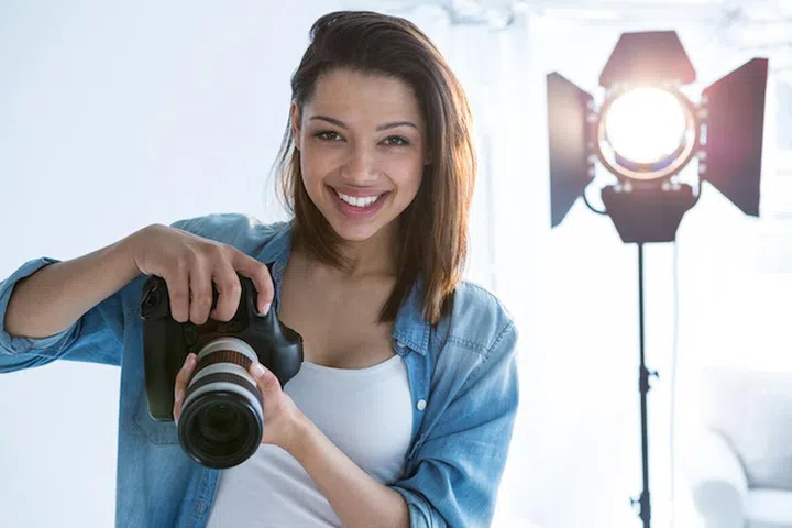 Portrait of happy female photographer standing in studio