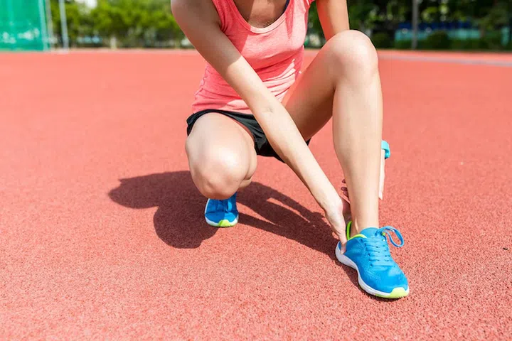 Sport woman getting hurt on legs in sport stadium