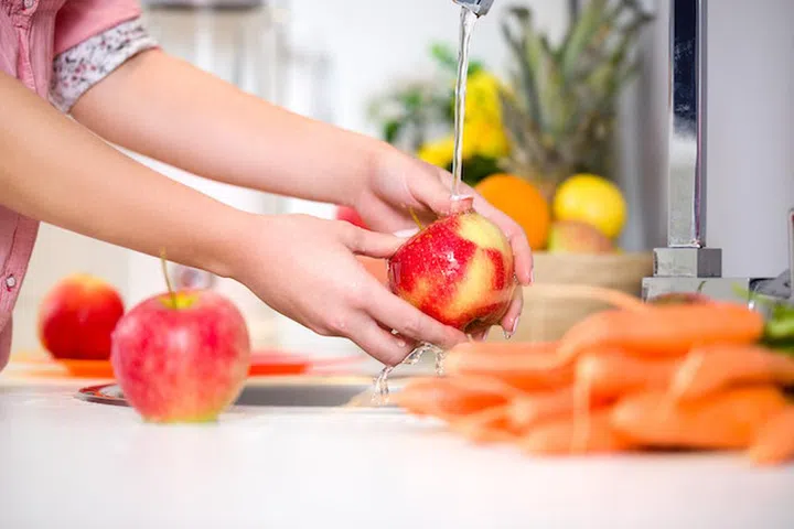 Woman hands washing tasty apple under the tap