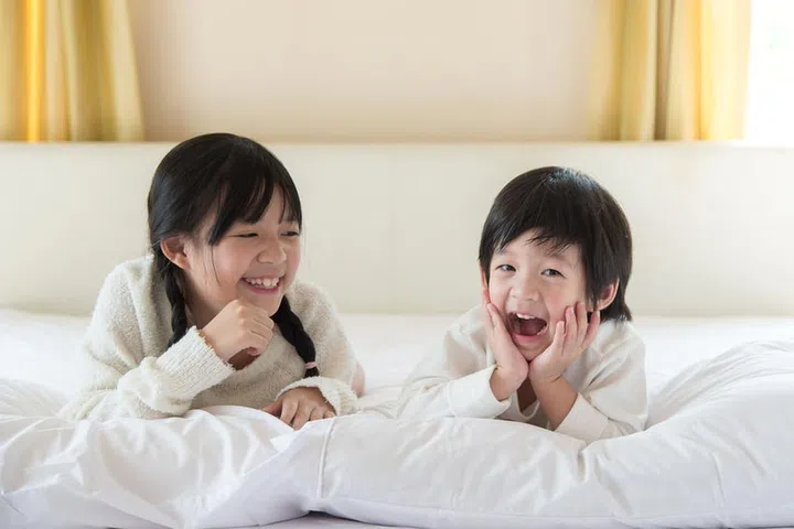 Cute asian children lying on white bed