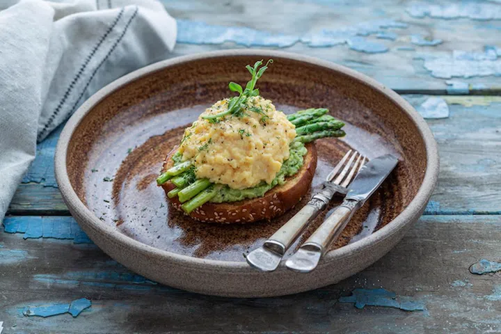 Healthy breakfast with scrambled eggs, avocado and asparagus, close view.