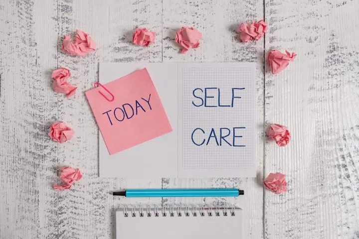 Text sign showing Self Care. Business photo text the practice of taking action to improve one s is own health Squared spiral notepad clip note highlighter paper balls wooden background