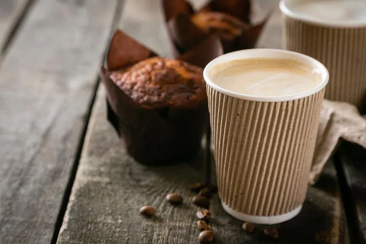 Coffee to go with muffin on wood background, copy space