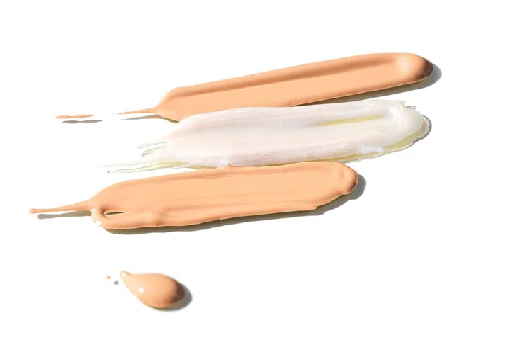 Texture of liquid foundation smears and lip gloss. Сosmetic tonal cream foundation liquid background. Abstract smudged smears. Flat lay, copy space. Close-up, isolated.