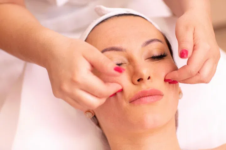 Woman undergoing a facial madero massage in welness center performed only with fingers of a masseuse