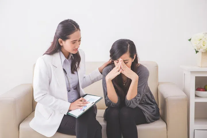 A portrait of Asian female patient crying while consulting her health problem with a female doctor