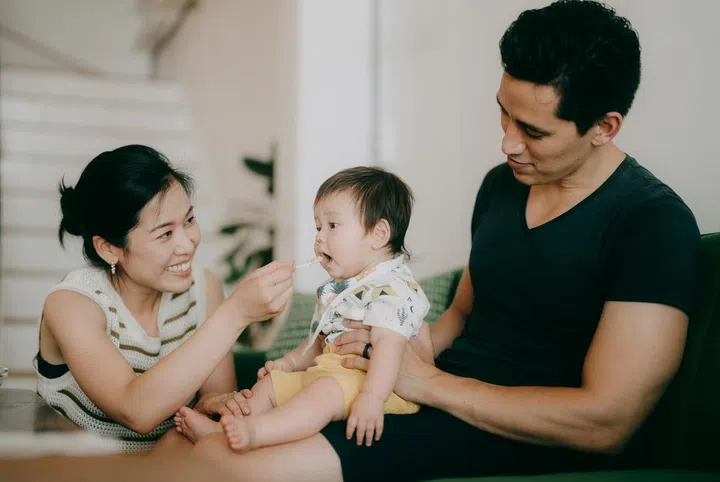 Parents feeding cute baby at home