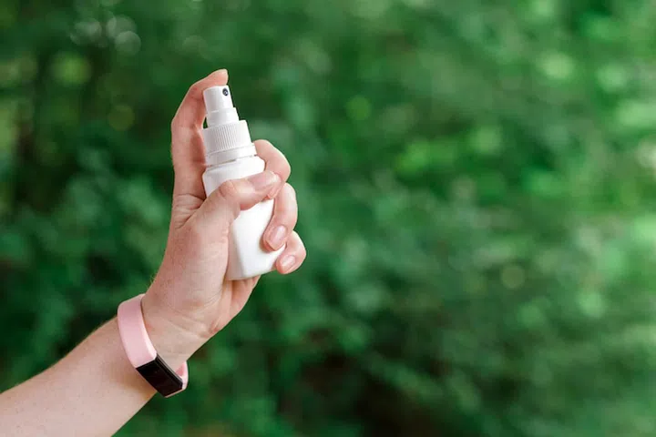 Woman using antiseptic spray outdoors in forest to protect the injury wound from infection, selective focus