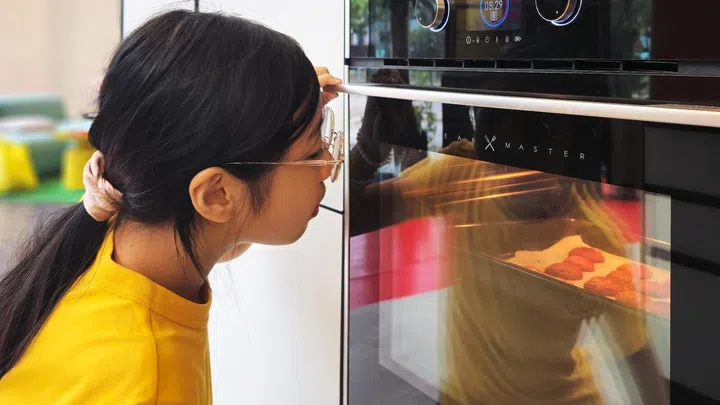 Magenta checking out the baking progress of their red velvet cookies. Photo credit: Elin Soo