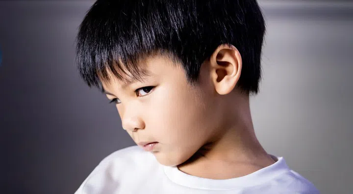 Portrait of angry tricky boy looking at camera