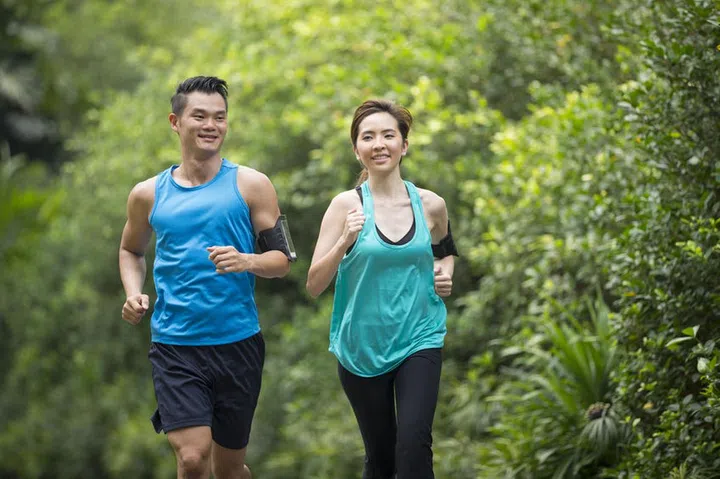 Athletic Asian man and woman running outdoors. Action and healthy lifestyle concept.