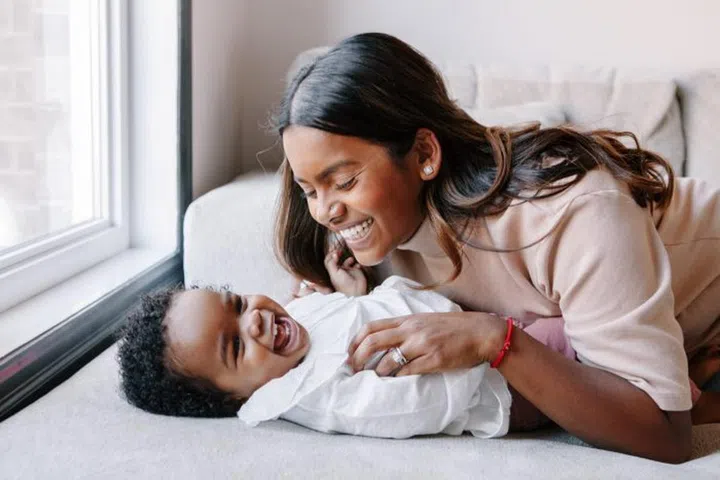 Happy smiling laughing Indian mother playing with black baby girl daughter. Family mixed race people mom and kid together hugging at home. Authentic candid lifestyle with infant kid child.