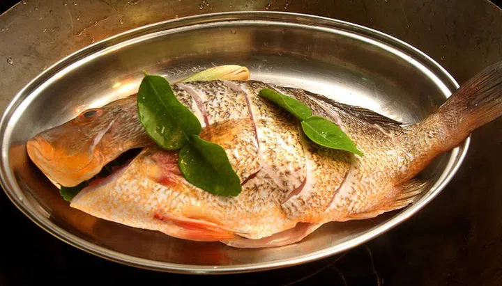 08. Place fish in a heatproof dish. Place four kaffir lime leaves on the fish.