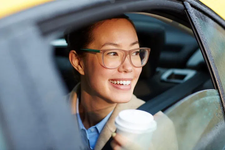 Attractive female in eyeglasses loking through car window after rain