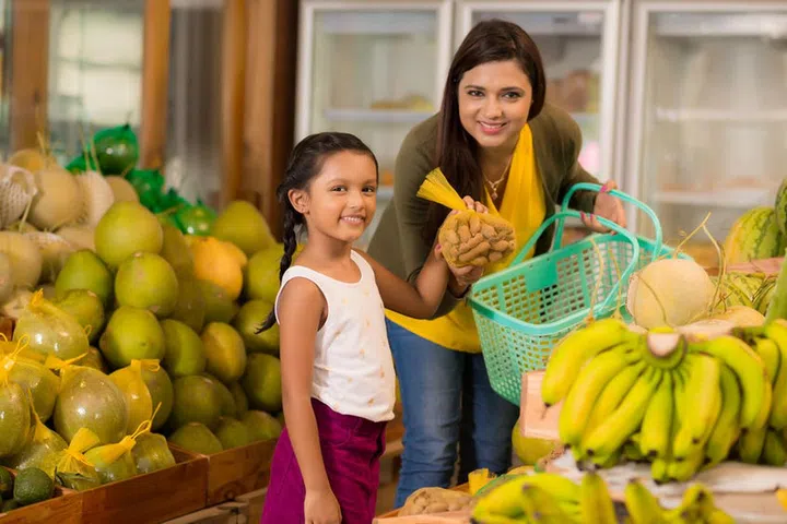 74737972 - indian mother and daughter buying sweet tamarind fruit at the grocery store