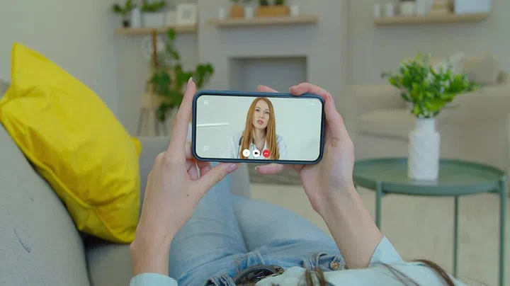 Girl using online chat to talk with professional therapist and checks possible symptoms during. Woman using medical app on smartphone consulting with doctor via video conference